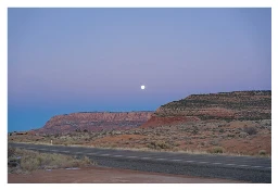 Cliffs in the early morning with a small full moon near the center. the sky is shades of blue and purple and you can see the earth shadow towards the bottom of the sky