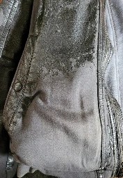 The image shows a close up of a pleather jacket with most of the shiny fake leather coating peeled off