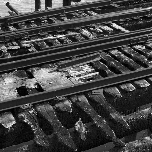 Detail of railroad tracks with charred ties on a pier.