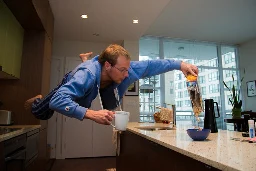 A photo of a man floating in the air above a kitchen counter pouring cereal into a bowl like this is a normal part of his weekend routine