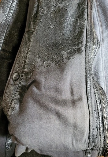 The image shows a close up of a pleather jacket with most of the shiny fake leather coating peeled off