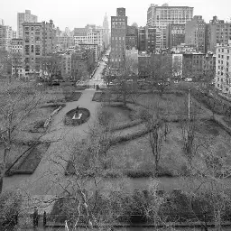 A fenced-in, formally landscaped urban park surrounded by buildings on a grey day. There are no people. You should leave now.
