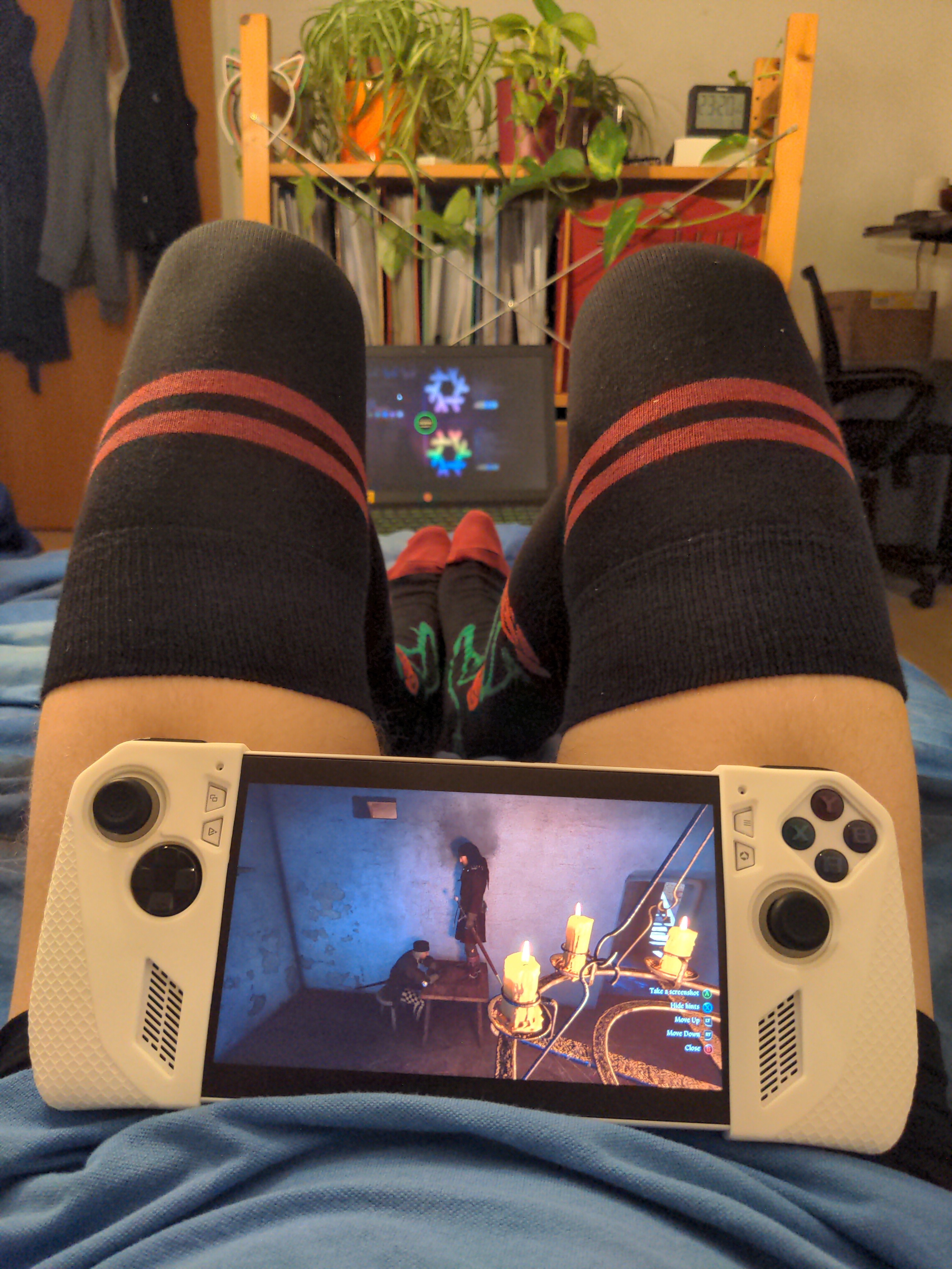 I am now playing Kingdom Come Deliverance 2 on the handheld, Henry is standing on the desk looking down on an NPC. My legs have been angled to support the Handheld being angled.